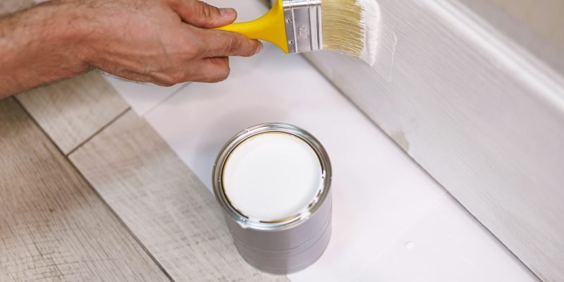 Applying white paint on wood door. Repair staining the doors with paint.